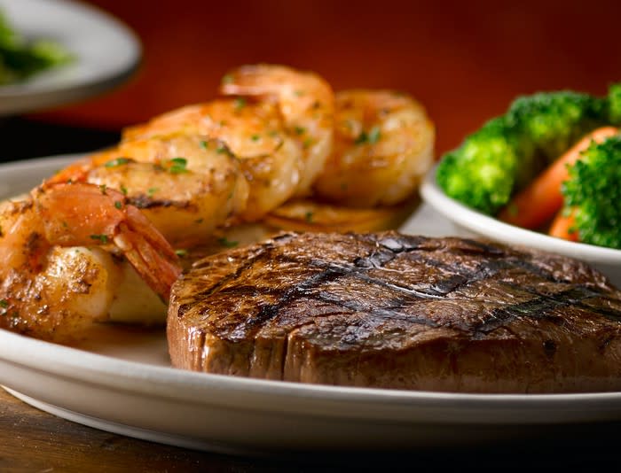 A plate with a steak, shrimp, and vegetables.