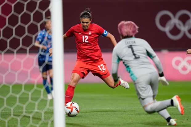 Canada's Christine Sinclair, left, scores her team's lone goal against Japan at the Olympic Games Tokyo 2020 on Wednesday in Sapporo, Japan. The Canadian captain now has 12 goals in 15 matches at the Olympics, having scored in four Olympic tournaments. (Silvia Izquierdo/The Associated Press - image credit)