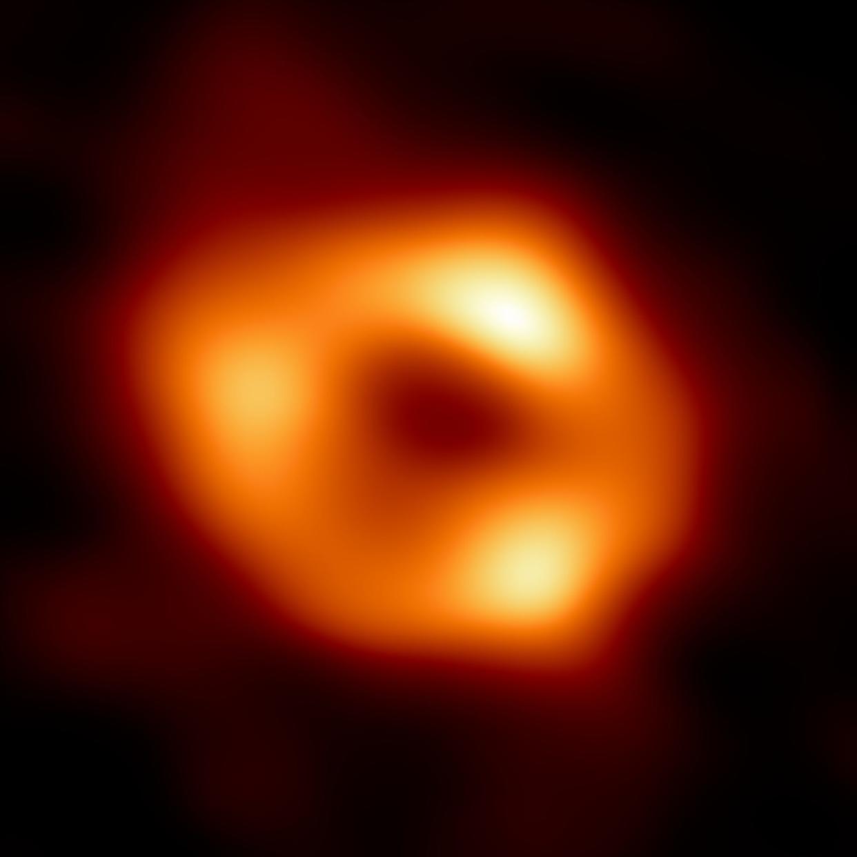 blurry red circle around a black center which represents the first photo of the supermassive black hole in our galaxy's center