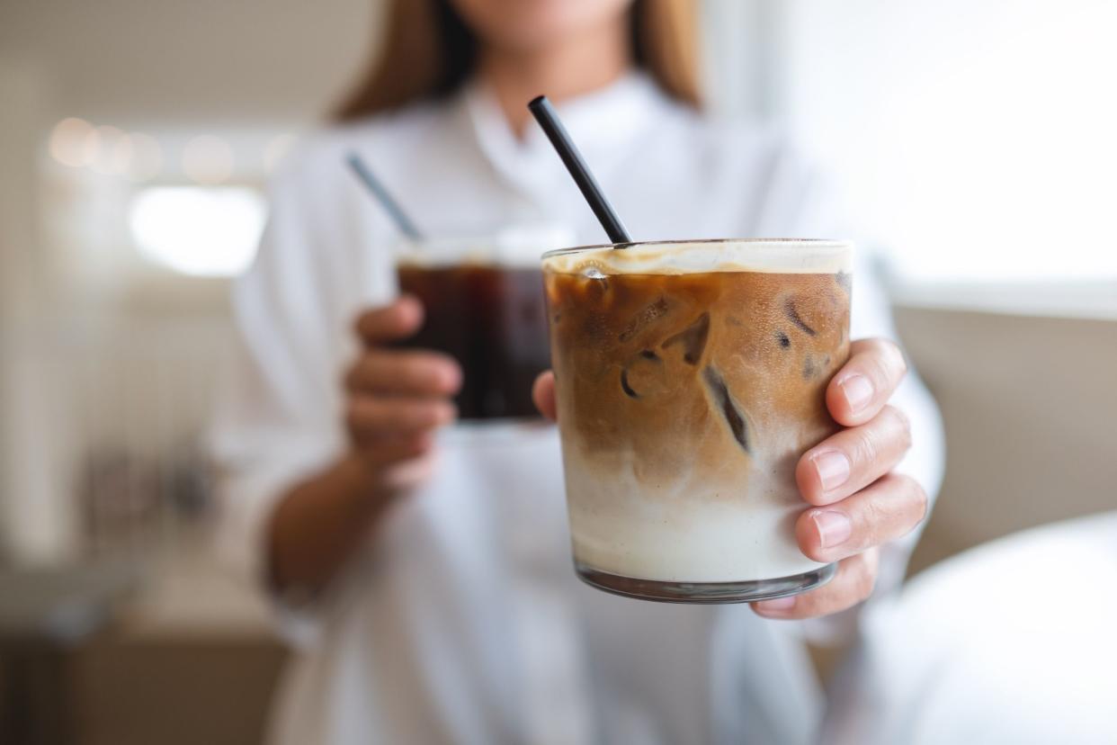 Close-up of a woman holding and pouring two glasses of iced coffee