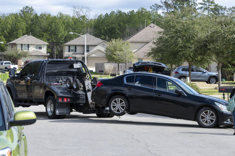 A car is towed from the driveway of a home in Conroe, Texas, where officers from multiple agencies visited on Monday Feb. 12, 2024, after a shooting at Lakewood Church in Houston left a woman dead and a child critically wounded. (Kirk Sides/Houston Chronicle via AP)