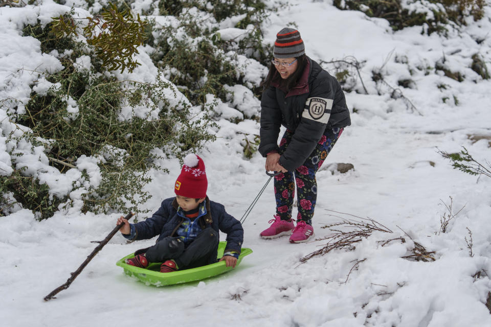 Aaron Lee, 7, and his mother play in the snow at the Deukmejian Wilderness Park, a rugged 709-acre site in the foothills of the San Gabriel Mountains, at the northernmost extremity of the City of Glendale, Calif., on Sunday, Feb. 26, 2023. (AP Photo/Damian Dovarganes)