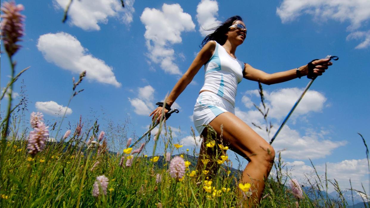  A woman Nordic walking through a meadow . 