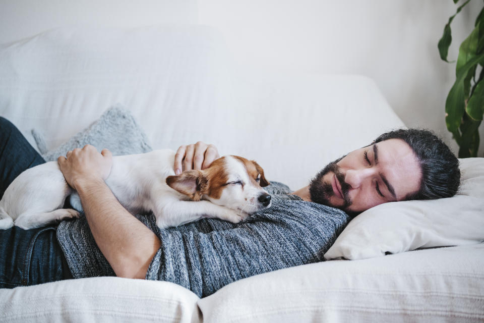 Man napping with dog. (Getty Images)