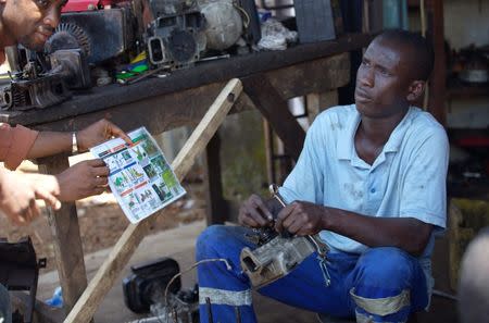 A social mobilizer from NGO Association des Jeunes Conditionnaires et Manutentionnaires (AJCOM), a UNICEF partner, uses an illustrated printout while speaking with a man about Ebola and best practices to help prevent its spread in Conakry, Guinea, in this handout photo provided by UNICEF taken September 15, 2014. REUTERS/Timothy La Rose/UNICEF/Handout via Reuters
