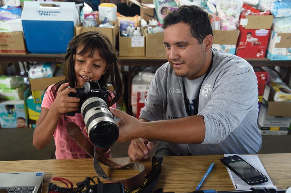 DEMING, N.M. – A migrant child and reporter Aaron Montes look at a photo in a migrant shelter in Deming, N.M.