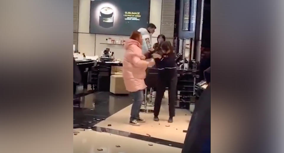 A large crowd gathers nearby as the woman appears to begin attacking a Chanel employee, grabbing her shirt sleeve as the worker desperately tries to get away. Source: Australscope