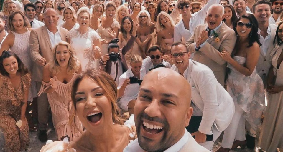 Influencers Kane Vato and Pia Muehlenbeck pose for a selfie with their wedding guests behind them.