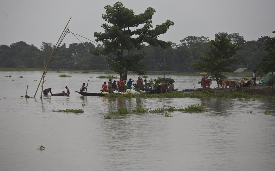 Indian flood affected villagers take shelter on a partially submerged road in Burha Burhi village, east of Gauhati, Assam, India, Monday, July 15, 2019. After causing flooding and landslides in Nepal, three rivers are overflowing in northeastern India and submerging parts of the region, affecting the lives of more than 2 million, officials said Monday. (AP Photo/Anupam Nath)