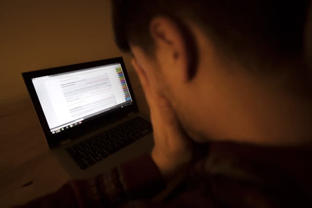 A teenager looking stressed with a laptop