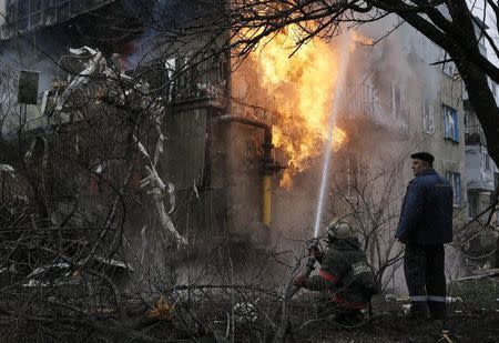 A firefighter works to extinguish a fire at a residential block, which was damaged by a recent shelling according to locals, on the outskirts of Donetsk, eastern Ukraine February 9, 2015. REUTERS/Maxim Shemetov