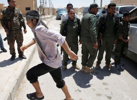 An Islamic State prisoner, who was pardoned by a council that is expected to govern Raqqa once the group is dislodged from the Syrian city, walks out of a van in front of Kurdish policemen in Ain Issa village, north of Raqqa, Syria June 24, 2017. REUTERS/Goran Tomasevic