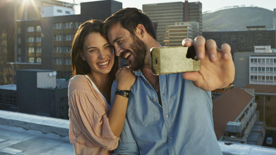 Man and woman smile as they take a selfie.