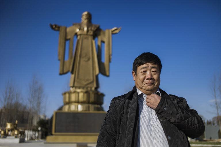 Former general Wang Dianming poses next to a Confucius statue in the seaside resort in Beidaihe, Hebei province, on December 12, 2014