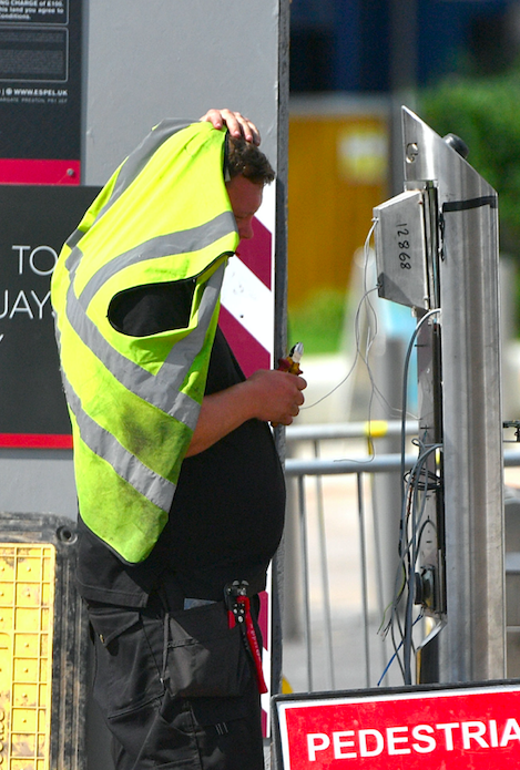 A Manchester worker uses his high-visibility vest to give him reprieve from the hot sun.