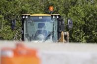 A front end loader remains at the scene where a forensic science investigator with the Pinellas County Sheriff's Office investigates the scene on the westbound lanes of I-275 near Gandy Boulevard on Friday, Sep 23, 2022, in St. Petersburg, Fla. Michael Hartwick, a Florida sheriff's deputy working an overnight shift to provide safety at a construction zone was struck and killed by a worker operating a front end loader, officials said.(Douglas R. Clifford/Tampa Bay Times via AP)