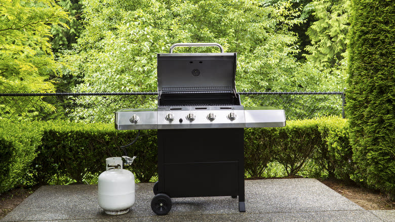 grill on concrete pad with propane tank