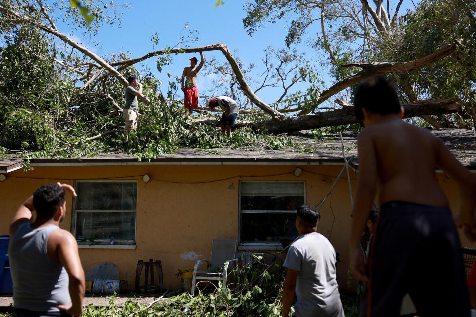 (L-R) Ken Pham, Lesman Varela, and Fernando Amador clear a large tree off their home after Hurricane Ian passed through on Sept. 29, 2022 in Fort Myers, Fla.<span class="copyright">Joe Raedle—Getty Images</span>