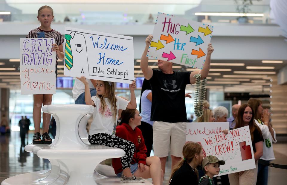 Sadie Schlappi, Millie Luke, Jerry Schlappi and Brooke Schlappi hold signs as they wait to welcome Elder Crew Schlappi home from serving a mission in Brazil at the Salt Lake City International Airport in Salt Lake City on Tuesday, June 20, 2023. | Kristin Murphy, Deseret News