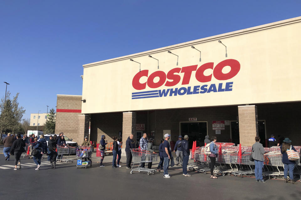 FILE - In this March 20, 2020 file photo, shoppers line up to enter a Costco store in Tacoma, Wash. Americans are beginning to see the first economic impact payments hit their bank accounts this week. The IRS tweeted Saturday, April 11, 2020, that it had begun depositing funds into taxpayers’ bank accounts and would be working to get them out as fast as it can. (AP Photo/Ted S. Warren, Fle)