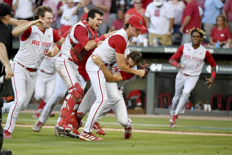 North Carolina State players, left to right, Dalton Feeney (19), Luca Tresh (24), Evan Justice (34) and Austin Murr (12) celebrate after beating Arkansas 3-2 to advance to the College World Series during an NCAA college baseball super regional game Sunday, June 13, 2021, in Fayetteville, Ark. (AP Photo/Michael Woods)