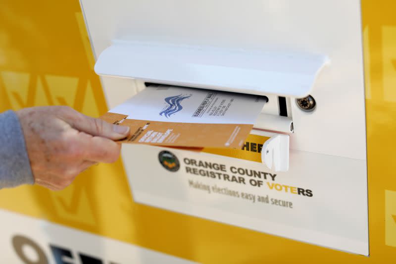 FILE PHOTO: A voter drops ballots for the March 3 Super Tuesday primary into a mobile voting mail box in Laguna Woods, California