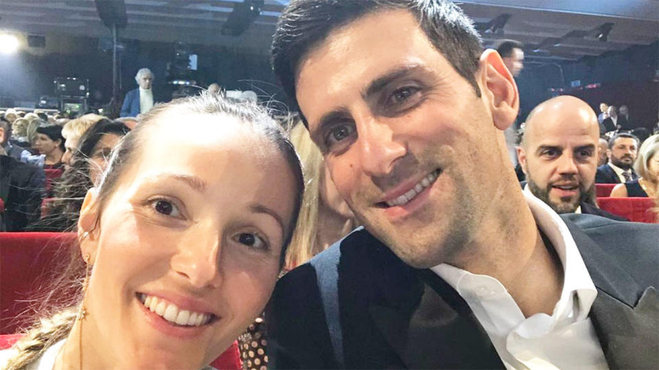 Seen here, Novak Djokovic and his wife Jelena pose together for a photo sitting amongst a crowd of people.