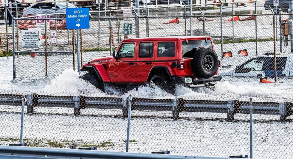 A Jeep drives on the perimeter road around the flooded runway on Thursday, April 13, 2023, at Fort Lauderdale-Hollywood International Airport, which remains closed due to the heavy rain.