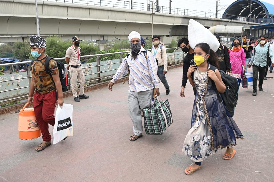 People arrive at a bus station in New Delhi on April 20, 2021, to leave for their native places as India battles a record-breaking spike in Covid-19 coronavirus infections that has forced the capital into a week-long lockdown. (Photo by Sajjad HUSSAIN / AFP) (Photo by SAJJAD HUSSAIN/AFP via Getty Images)