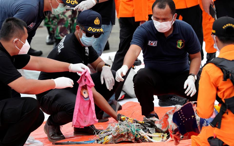 Investigators sort debris found on the waters off Java Island around where a Sriwijaya Air passenger jet crashed - AP