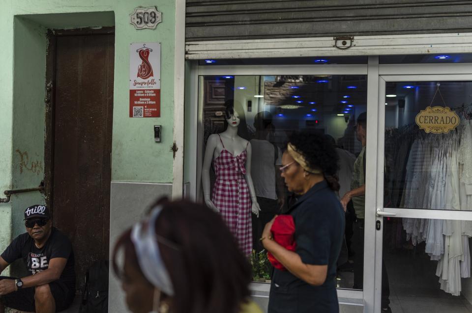 Residents walk past a closed, private clothing store in Havana, Cuba, Saturday, Nov. 11, 2023. Locals refer to small private stores as “mipymes” - pronounced MEE-PEE-MEHS and the name derives from the Spanish words for the small- and medium-sized enterprises that were first allowed to open in 2021. (AP Photo/Ramon Espinosa)