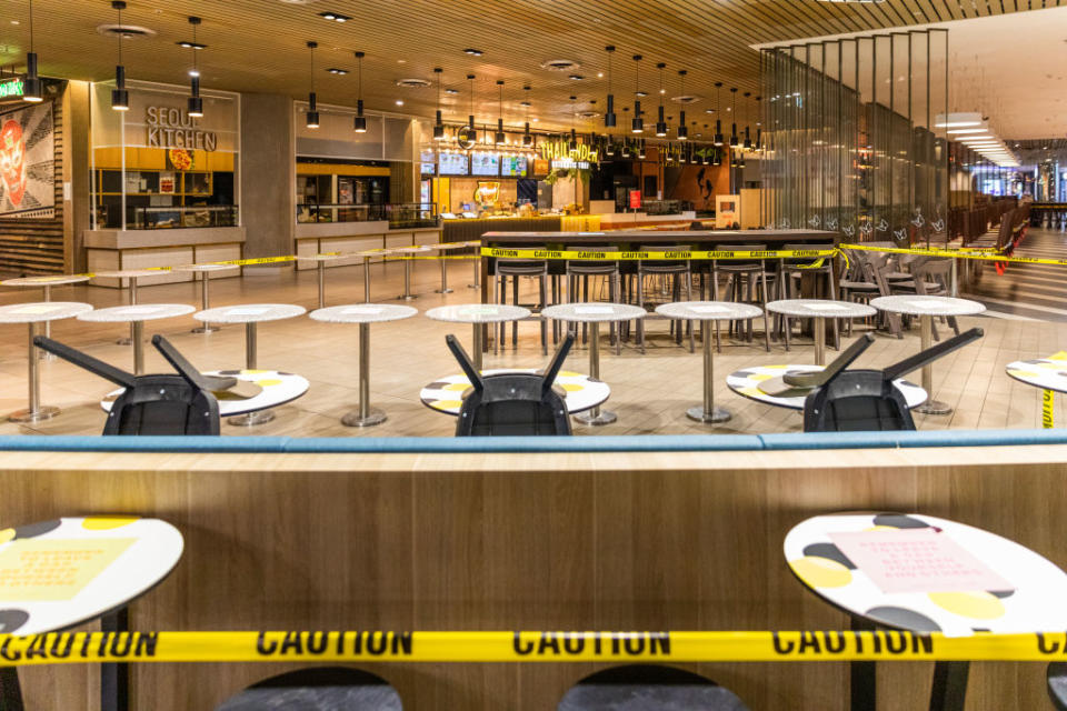 An empty foodcourt with chairs stack on tables and caution taped around a Melbourne dining hall.