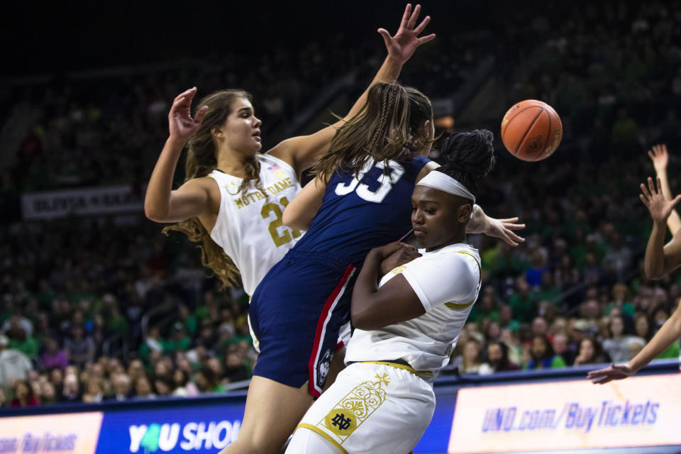 Connecticut's Caroline Ducharme (33) gets called for a charge on Notre Dame's KK Bransford, right, as Maddy Westbeld (21) also defends during the second half of an NCAA college basketball game on Sunday, Dec. 4, 2022, in South Bend, Ind. (AP Photo/Michael Caterina)