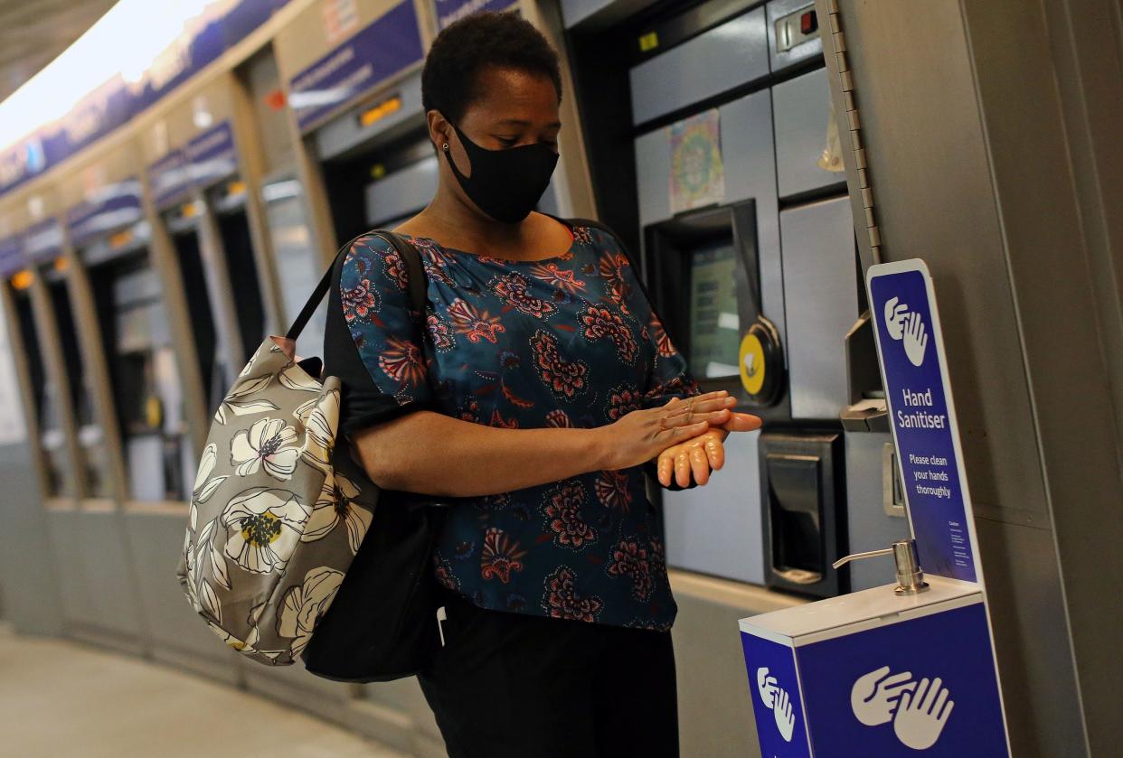 A passenger wearing PPE (personal protective equipment) of a face mask as a precautionary measure against COVID-19, uses a newly installed Hand Sanitser station to clean their hands as they pass through King's Cross St Pancrass TfL (Transport for London) Underground station in central London on May 20, 2020. - Britain's official coronavirus death toll is at least 41,000 with almost 10,000 dead in care homes in England and Wales alone, according to a statistical update released on Tuesday. Some 41,020 deaths where COVID-19 was mentioned on the death certificate were registered across the UK by May 8, according to the Office for National Statistics (ONS). (Photo by ISABEL INFANTES / AFP) (Photo by ISABEL INFANTES/AFP via Getty Images)