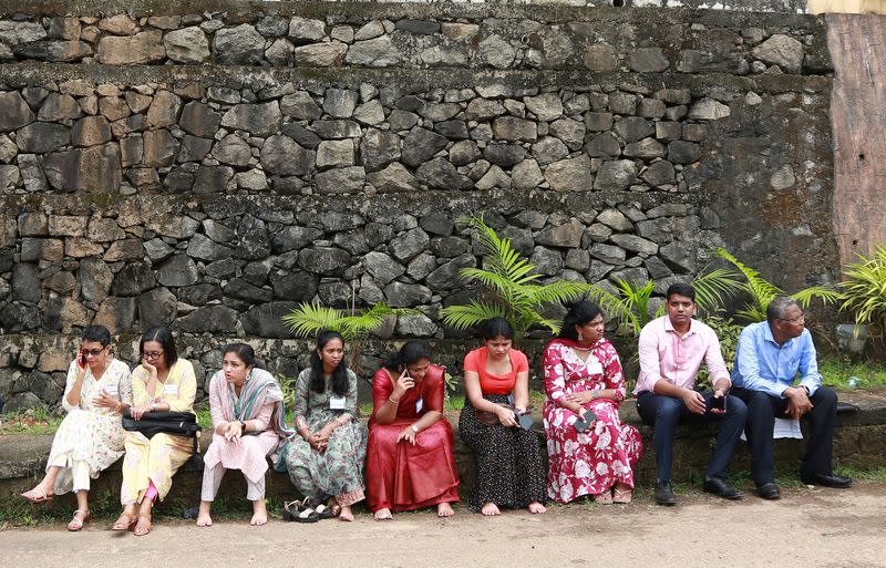 People, who were evacuated from a convention centre following multiple blasts during a religious gathering, sit outside the centre, in Kochi