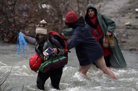 Refugees and migrants cross a river near the Greek-Macedonian border to return to Greece, after an unsuccessful attempt to enter Macedonia, west of the village of Idomeni, Greece, March 15, 2016. REUTERS/Alexandros Avramidis