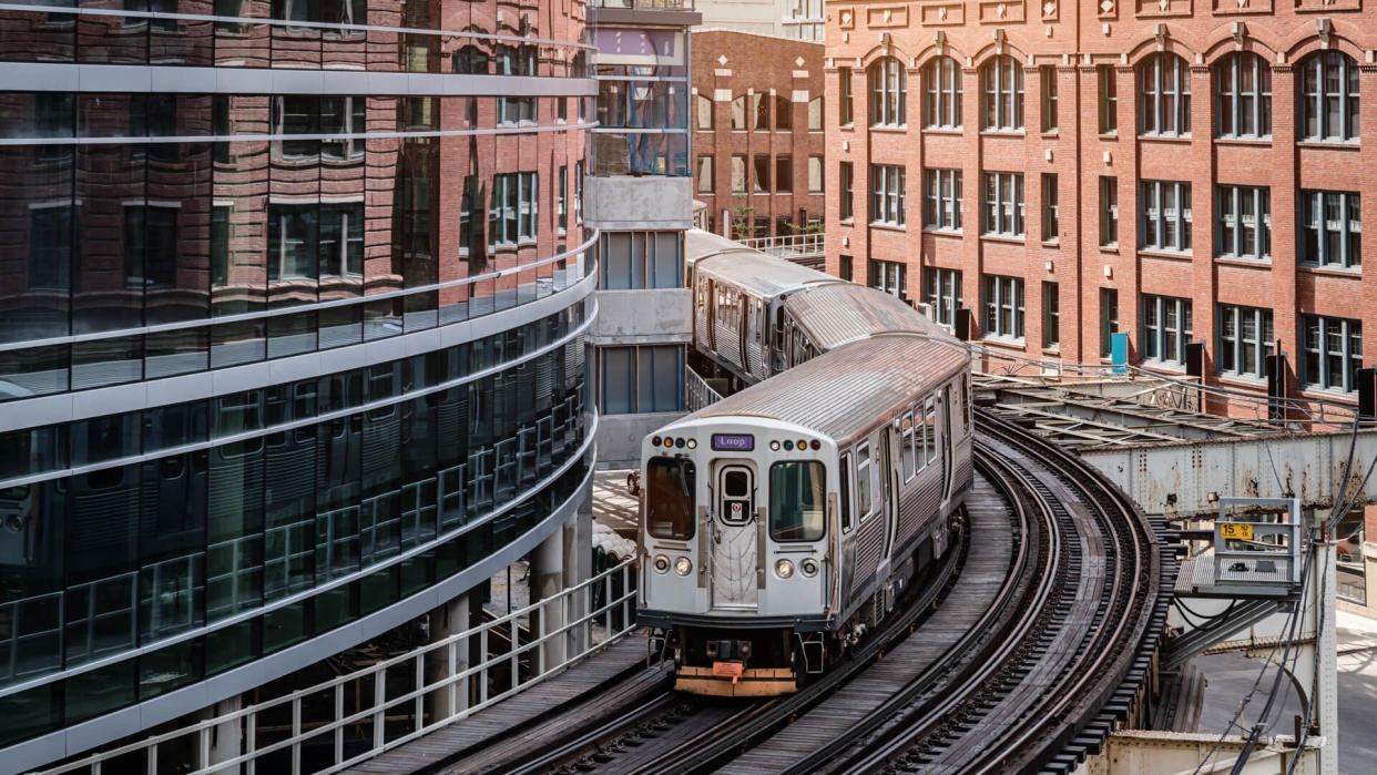 Chicago typical silver colored commuter train moving on elevated tracks to railroad station in between urban city buildings of Chicago, Illinois, USA.