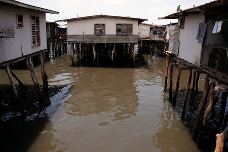 A woman washes as she stands outside her home located in the stilt houses village of Hanuabada, located in Port Moresby Harbour in Papua New Guinea, November 19, 2018. Picture taken November 19, 2018. REUTERS/David Gray