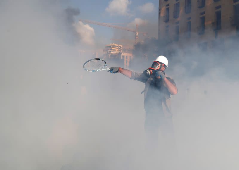 A demonstrator uses a tennis racket to return a tear gas canister to riot police, during a protest in Beirut