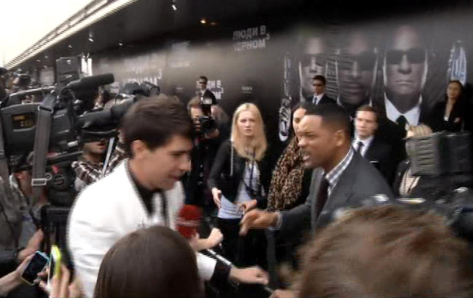 In this video image taken from AP video U.S. actor Will Smith, center right, reacts after he was embraced by reporter Vitalii Sediuk, white suit, from the Ukrainian television channel 1+1 on the red carpet before the premiere of "Men in Black III" Friday May 18, 2012 in Moscow. Hollywood star Will Smith has slapped a male television reporter who tried to kiss him before the Moscow premiere of "Men in Black III." Smith pushed him away and then slapped him lightly across the cheek with the back of his left hand. (AP Photo via AP video)