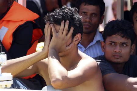 A migrant covers his face before disembarking a coast guard ship at the Sicilian harbour of Augusta August 26, 2014. REUTERS/Antonio Parrinello