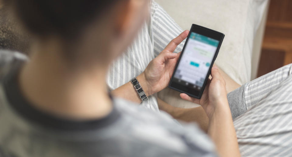 A stock image of a person on their phone reading text messages.