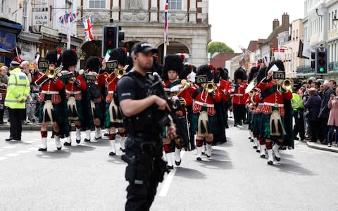 Armed police stand guard as the Royal Regiment of Scotland band march by, on the high street in Windsor on Tuesday - Credit: Alastair Grant/AP