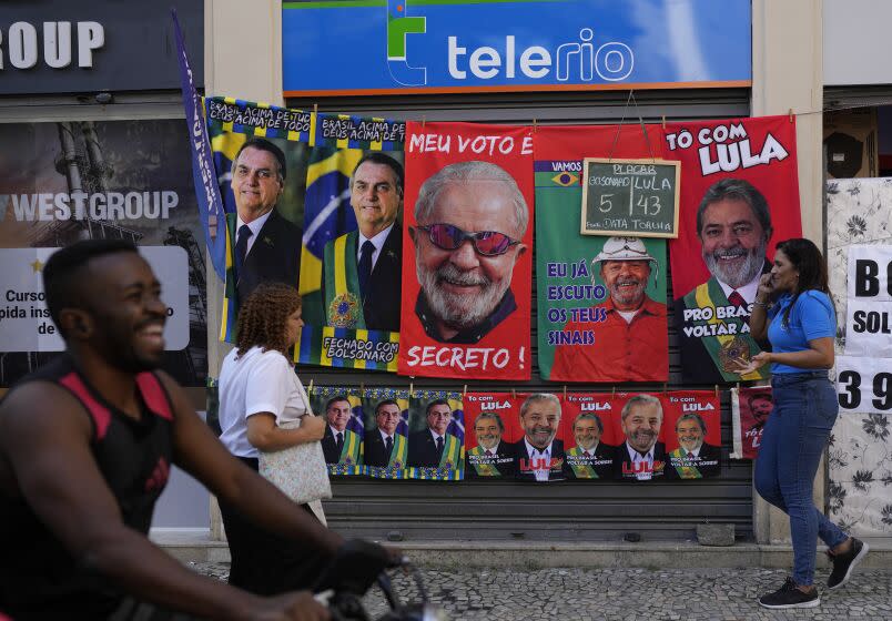 Towels featuring President Jair Bolsonaro, left, and former President Luiz Inacio da Silva, or Lula, hang for sale next to a chalkboard showing the vendor's daily sales count for each presidential contender towel, ahead of elections in Rio de Janeiro, Brazil, Wednesday, July 27, 2022. General elections are set for Oct. 2. (AP Photo/Silvia Izquierdo)