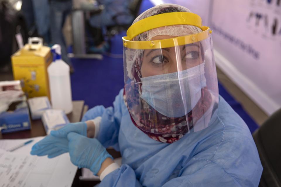 A health worker wearing protective gear prepares to take swab samples from people lining up in their cars to test for the coronavirus at a drive-through COVID-19 screening center at Ain Shams University in Cairo, Egypt, Wednesday, June 17, 2020. (AP Photo/Nariman El-Mofty)