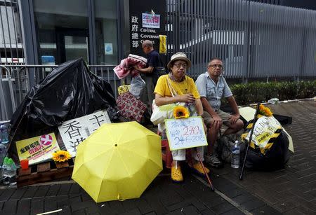 Several of the remaining pro-democracy protesters, before their tent was demolished, sit outside the government headquarters in Hong Kong, China June 24, 2015. REUTERS/Bobby Yip