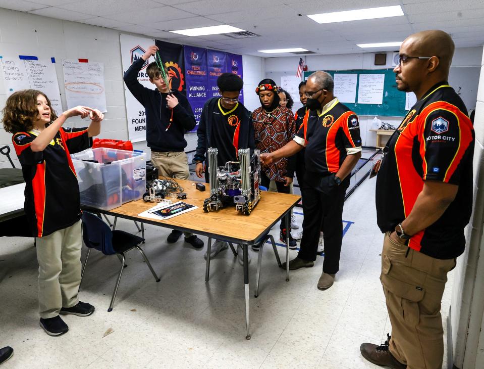 Joshua Baker, left, talks with lead robotics coach Leon Pryor before practice as other students and a coach talk about their robot in the basement of the Foreign Language Immersion And Cultural Studies School in Detroit on Friday, Feb. 10, 2023. The team qualified for the world robotics championship that happens in Houston in April. It is the first Detroit middle school to compete in it.