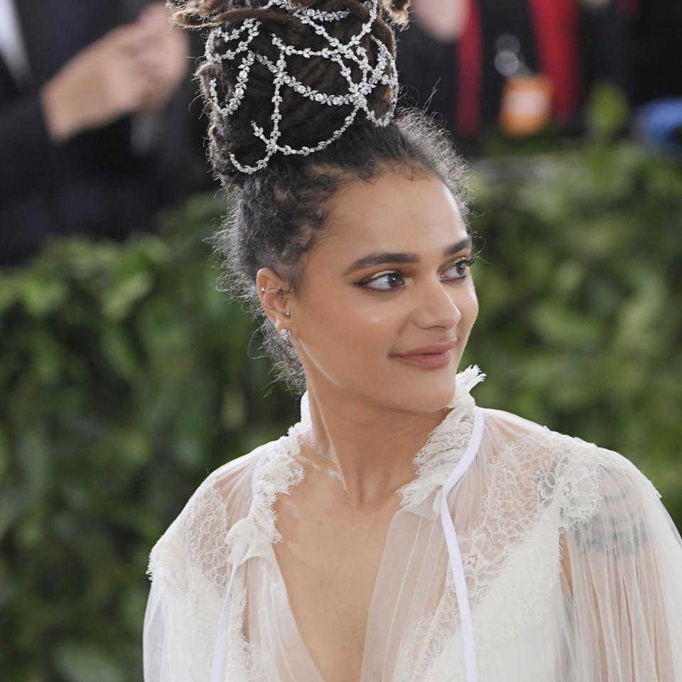 Rising actress Sasha Lane debuts an elaborate updo with crystal detail on the 2018 Met Gala red carpet.