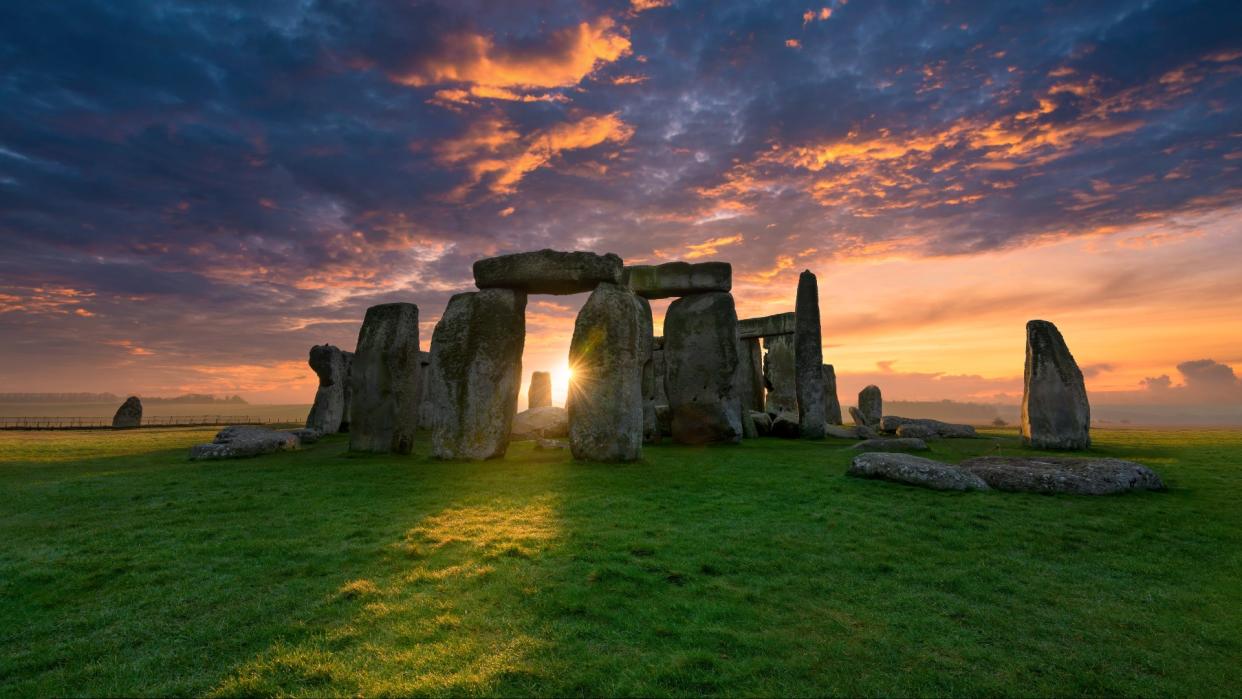  Photo of Stonehenge as the sun is peaking between the stone arches. 