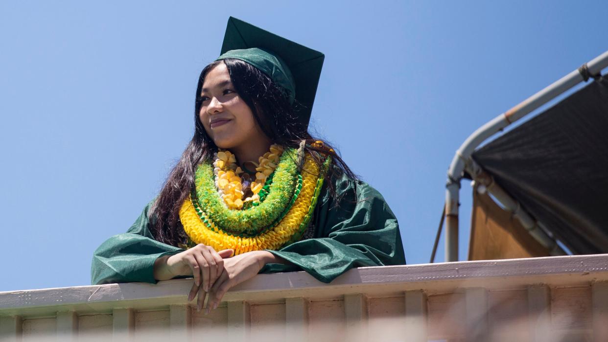 Gemalyn Yutob, a Leilehua High School graduate, wears various leis over her graduation gown at her home in Wahiawa, Hawaii, on May 23.